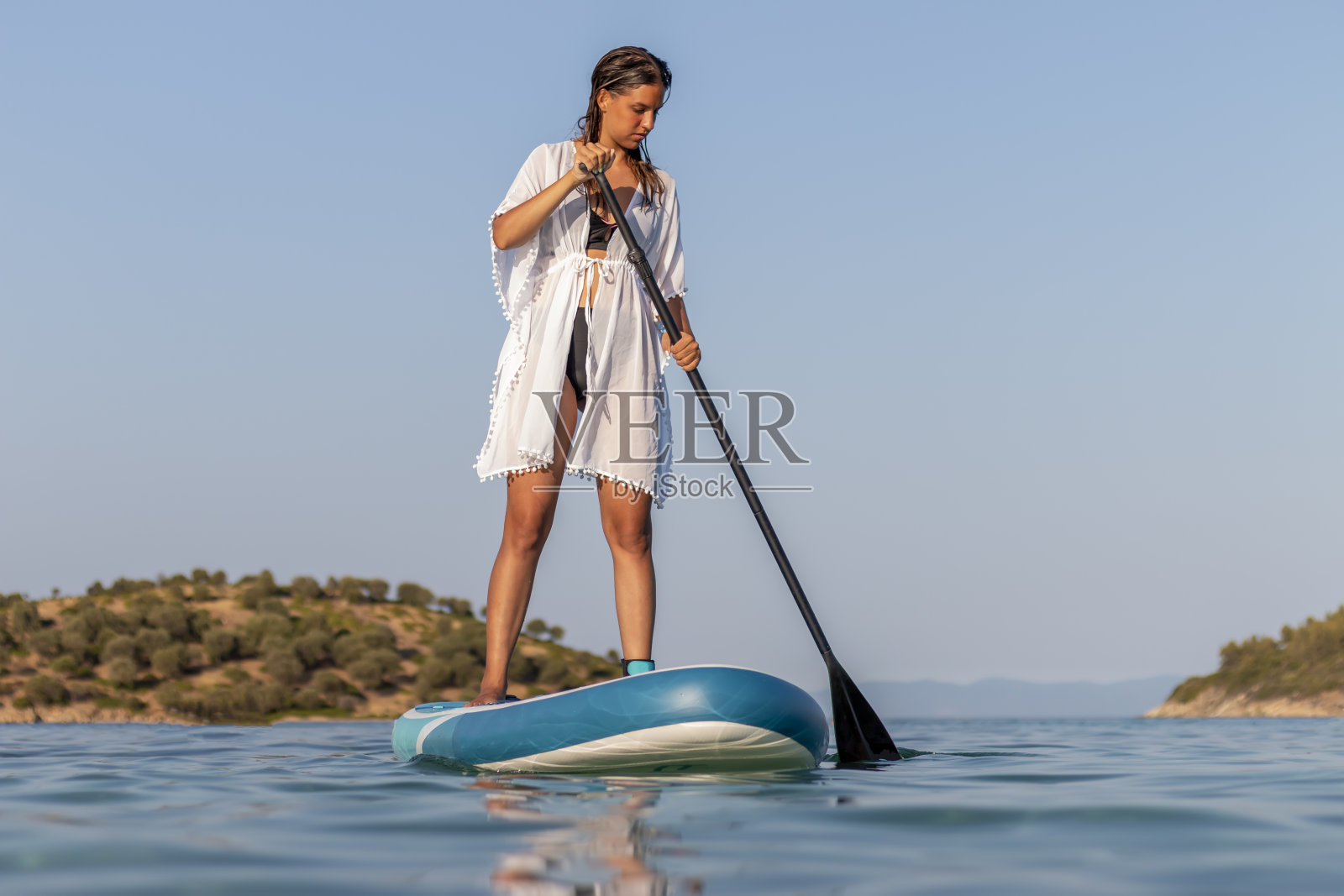 年轻的女孩在海上冲浪板上穿着白色的裙子照片摄影图片