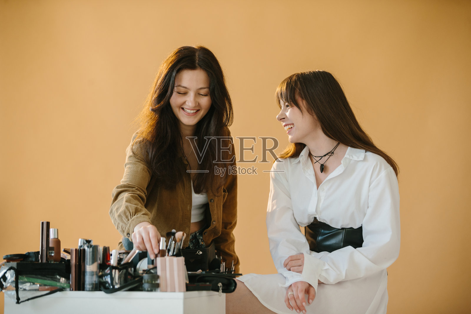 化妆师在摄影工作室用米色背景为女模特做准备照片摄影图片