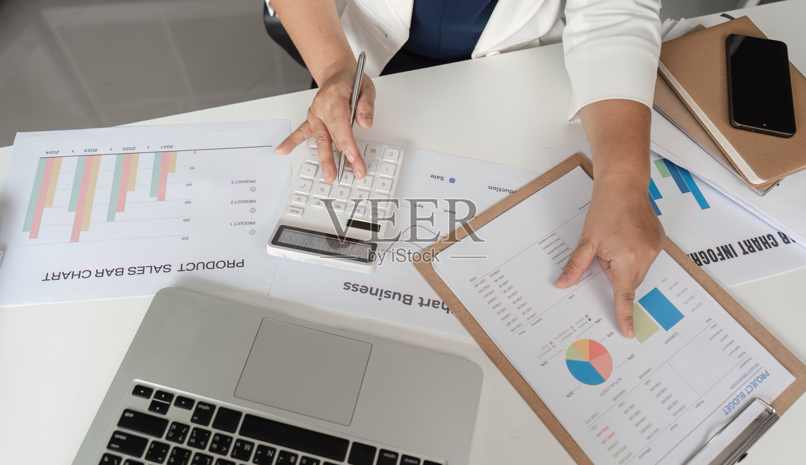 中年女会计用计算器和图表分析桌上的财务文件照片摄影图片