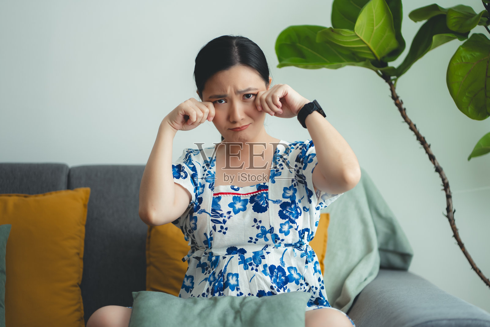 亚洲孕妇坐在家里的客厅里看着镜头伤心哭泣。照片摄影图片