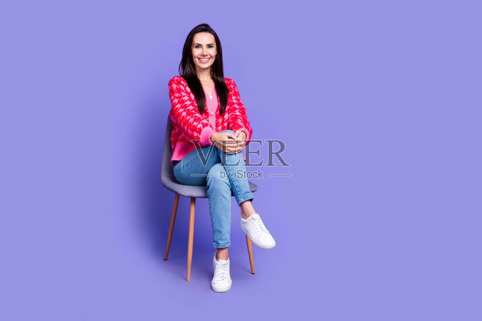 全身照片开朗漂亮的女士穿着粉红色的开襟羊毛衫坐在椅子空的空间孤立的紫罗兰色背景照片摄影图片