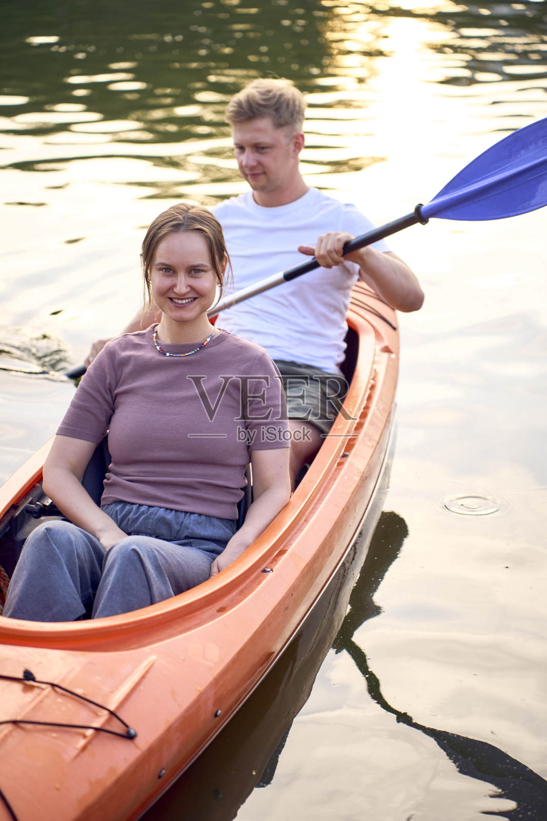 那对相爱的夫妇在日落时分在河上划皮艇照片摄影图片