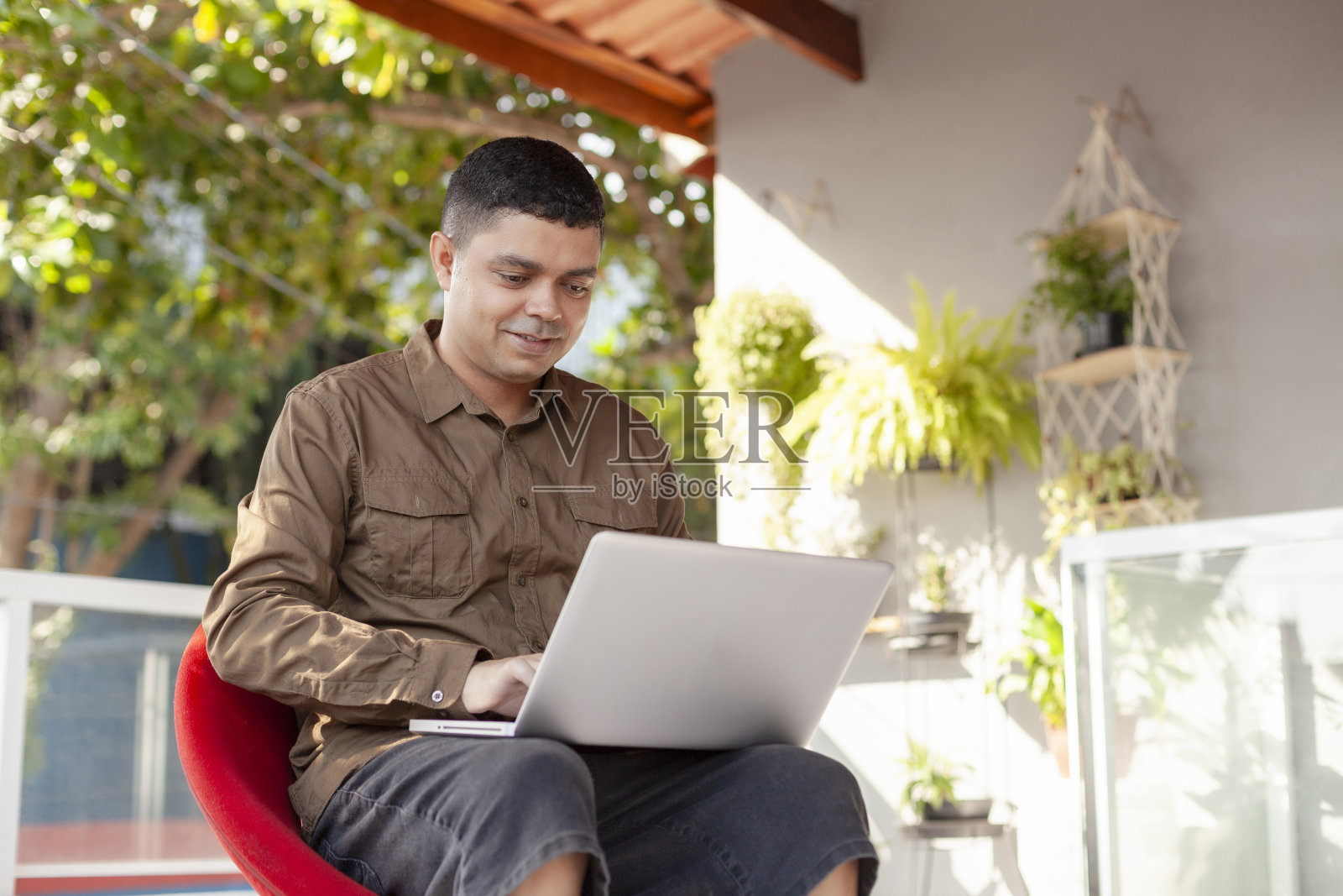 一个巴西人,坐在家里的阳台上用电脑工作。照片摄影图片