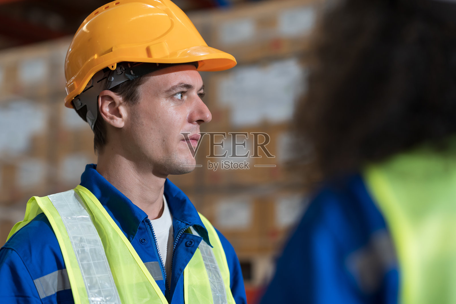 在仓库工作的仓库工人。男女工人在仓库里讨论照片摄影图片