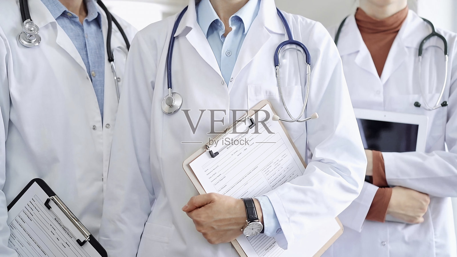 一群医生穿着白大褂,戴着听诊器,拿着写字板站在那里。医疗小组在工作照片摄影图片