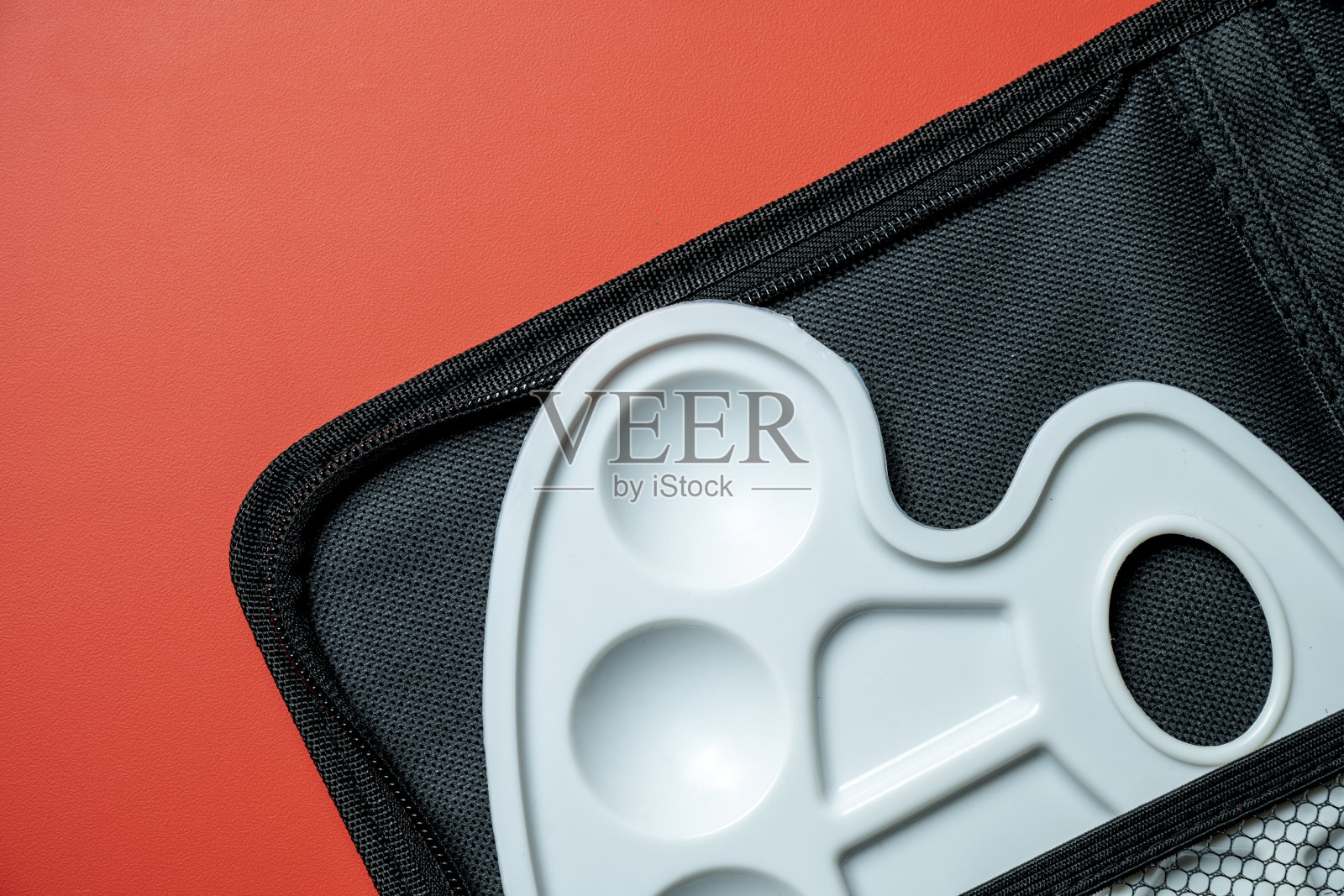 一个白色的调色板放在一个红色背景上的黑色盒子里照片摄影图片