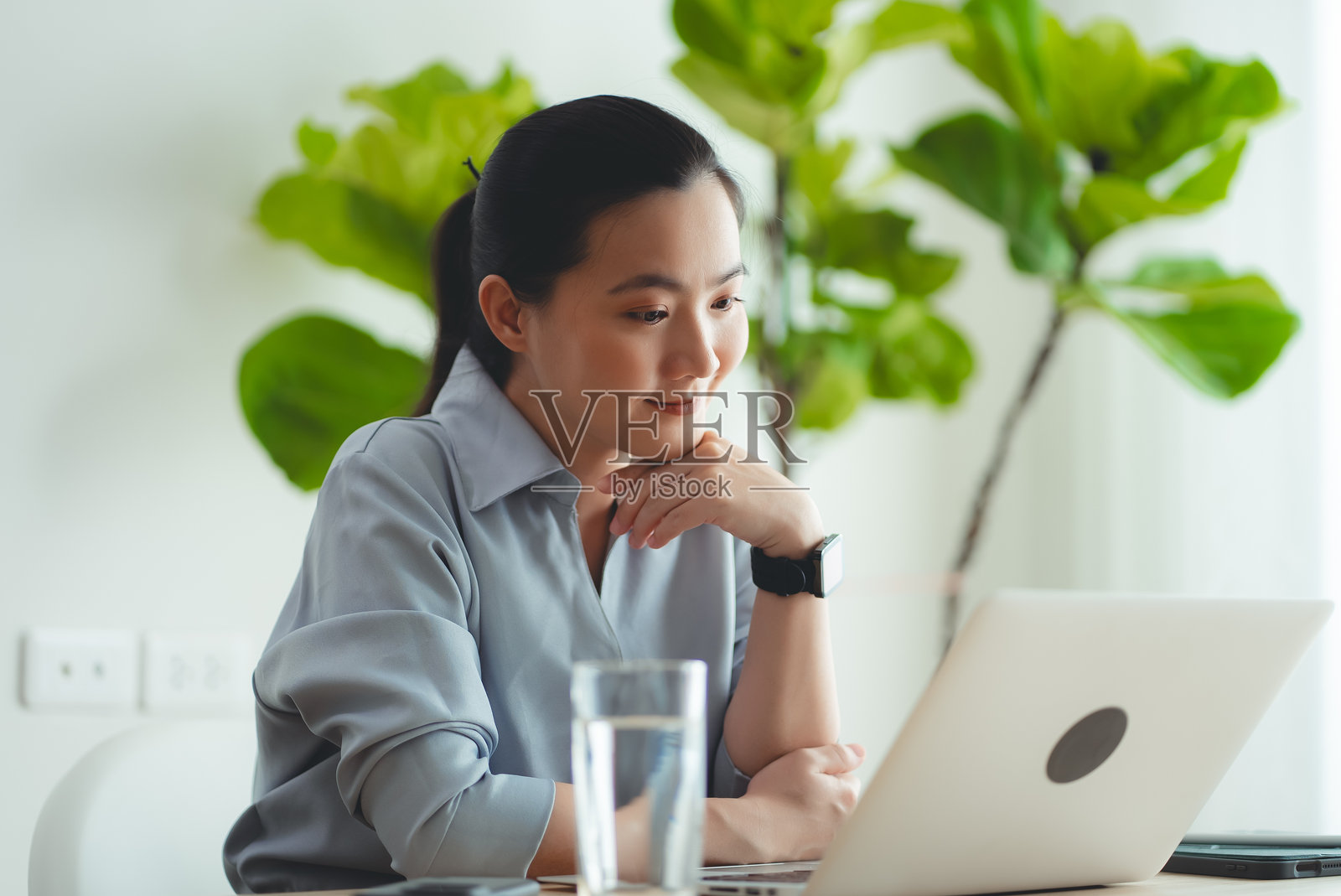 亚洲女性喜欢坐在家里用笔记本电脑上网工作。照片摄影图片