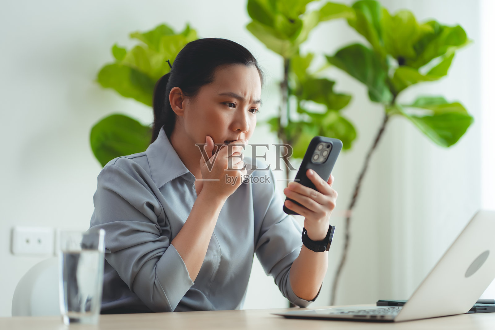 使用智能手机的亚洲女性正在遭受工作或财务问题的困扰。照片摄影图片