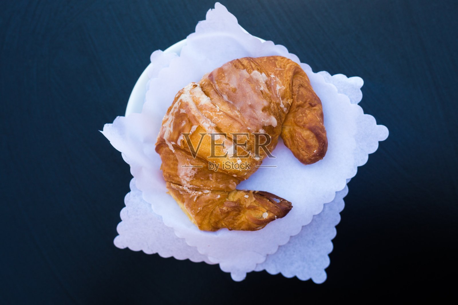 意大利早餐。俯瞰新鲜的传统法式羊角面包,在白色餐巾上涂上釉。黑色背景和复制空间。正宗的意大利早餐面包店。经典欧式早餐照片摄影图片