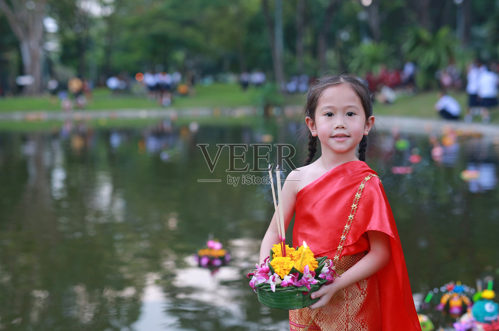 在泰国的节日里,亚洲的小女孩穿着泰国传统服装,手持祈求宽恕女神恒河的礼券庆祝节日。照片摄影图片