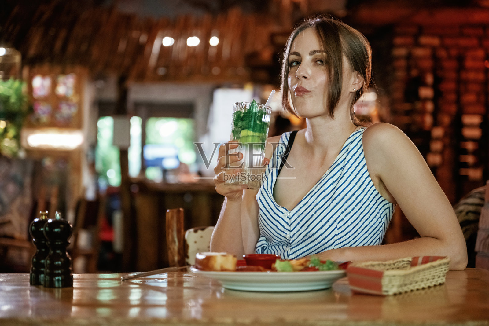 新鲜的莫吉托已经准备好了。女人在餐厅里拿着食物和饮料照片摄影图片