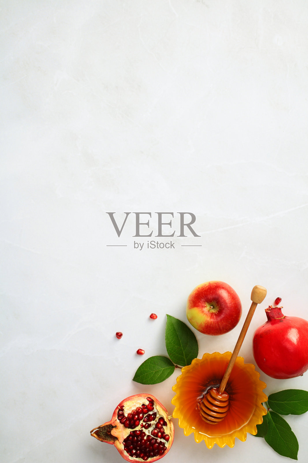 犹太节日Rosh Hashanah庆祝活动。石桌上平放着蜂蜜、苹果和石榴。照片摄影图片