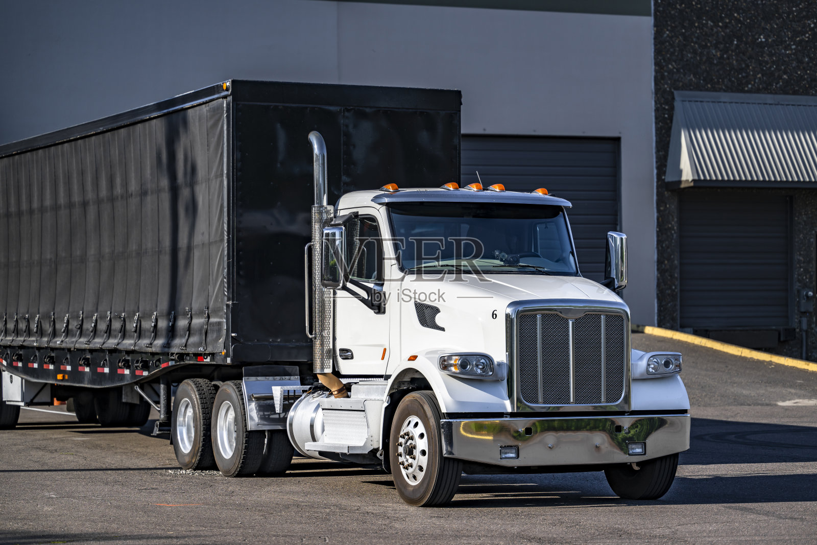 强大的白天驾驶室白色大钻机半挂车与黑色康内斯托加平板半挂车站在仓库码头装载货物为下一个货运照片摄影图片