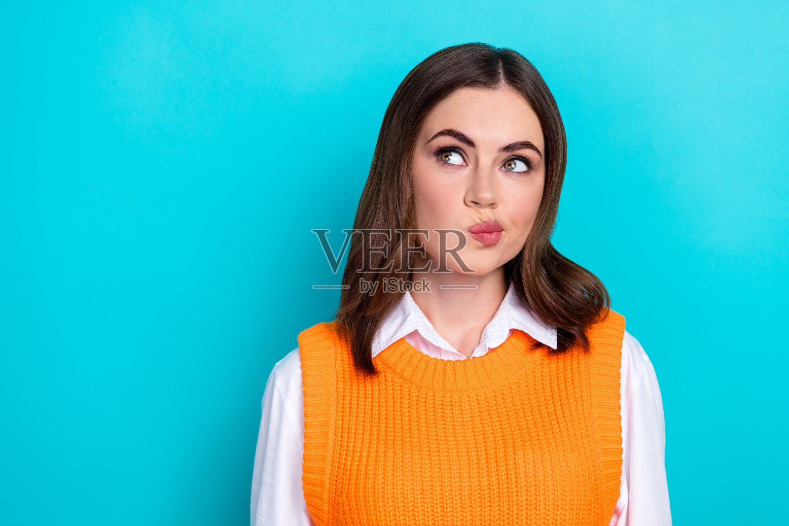 正面、体贴、聪明的女孩的肖像,直发,穿白衬衫,在绿松石色的背景上看起来空无一物照片摄影图片