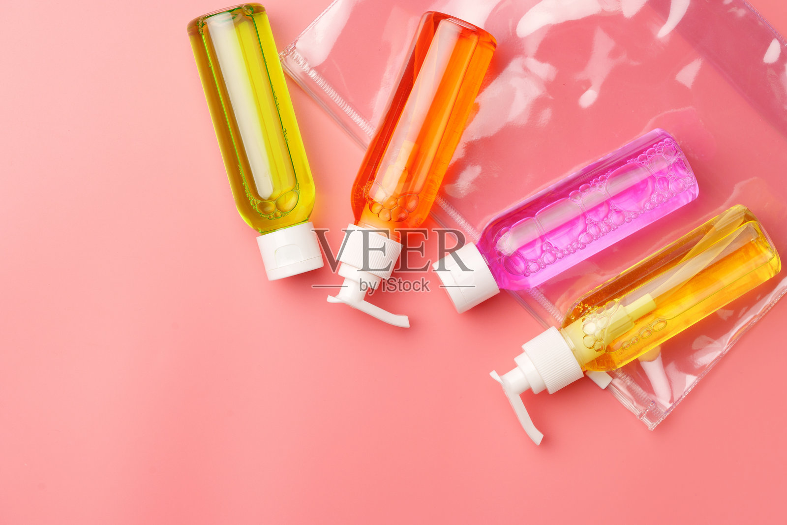 透明塑料袋包含旅行大小的化妆品在粉红色的背景照片摄影图片