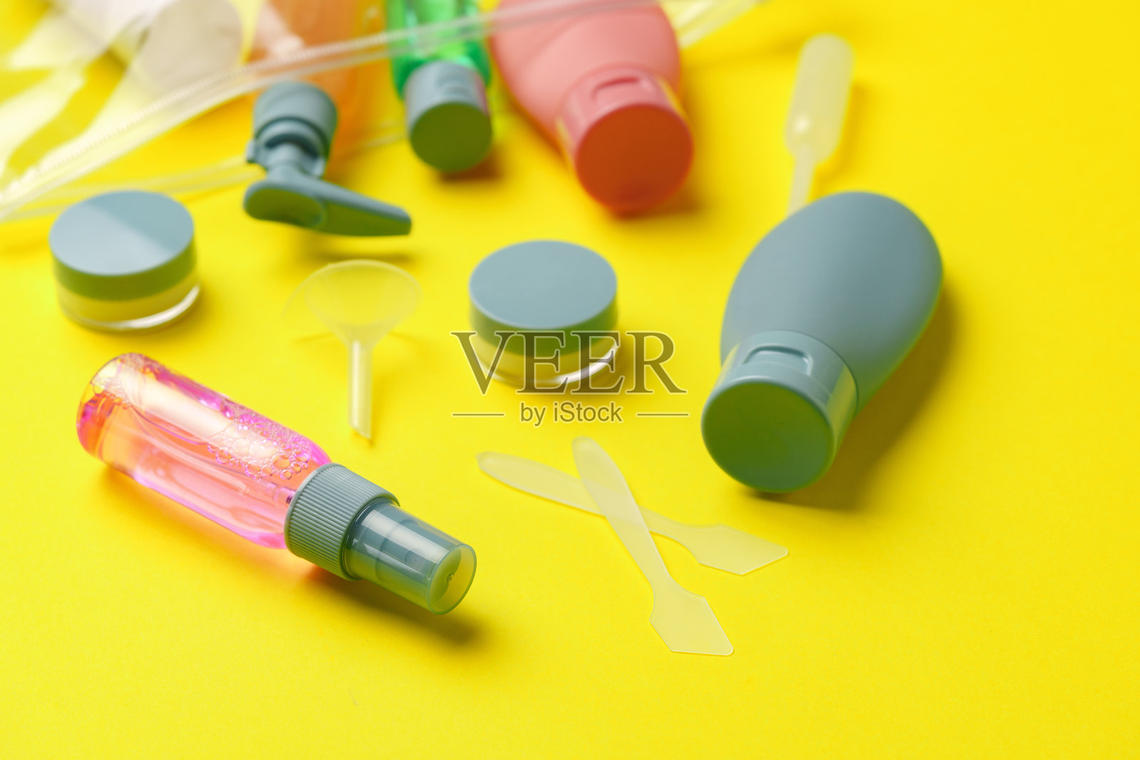 旅行尺寸的瓶子和容器装在一个黄色背景的袋子里照片摄影图片