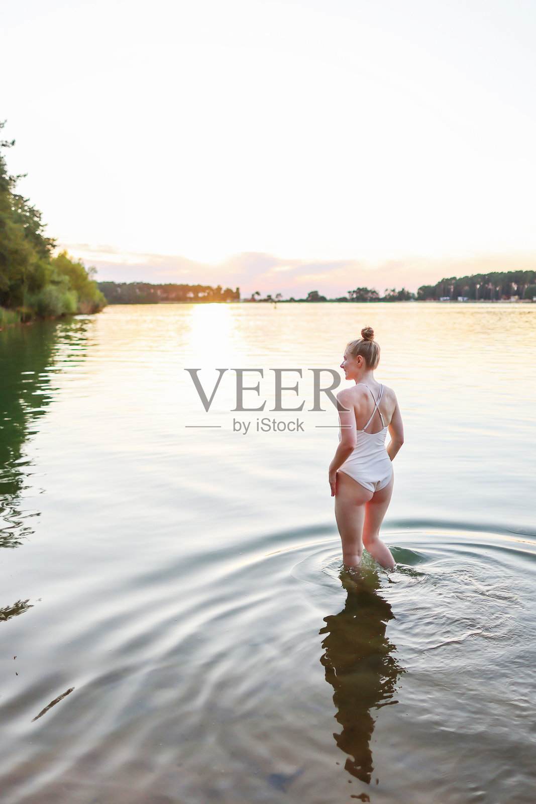 日落时分,女孩在湖上游泳照片摄影图片