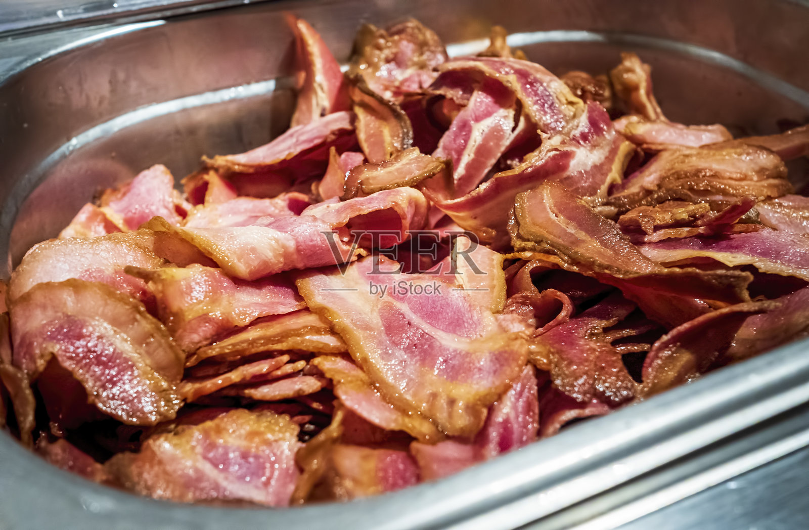 在加热的盘子里煎炸的脆脆的培根片照片摄影图片