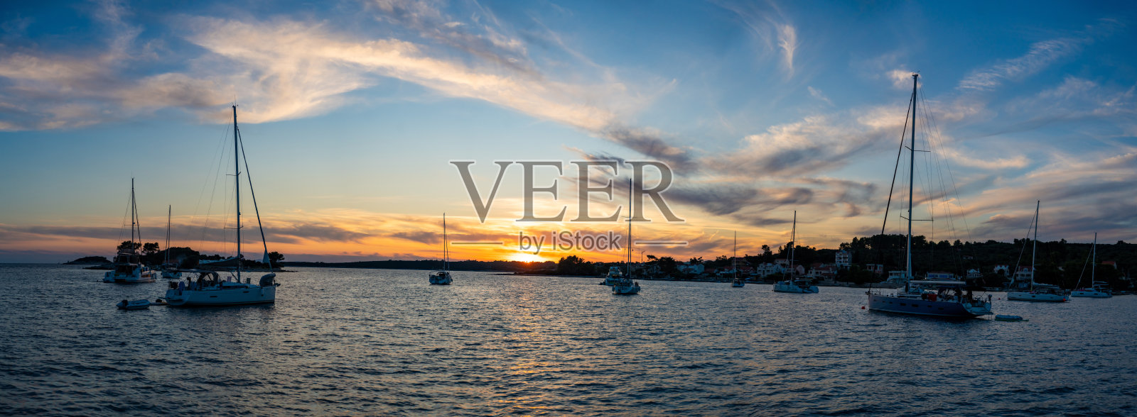 日落时分,克罗地亚科尔库拉岛维拉卢卡镇附近的乌瓦拉格拉迪纳湾,停泊在岸边浮标上的游艇全景照片摄影图片