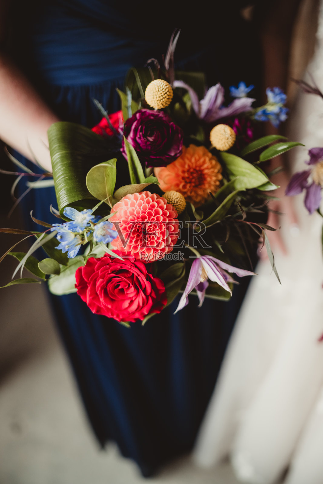 伴娘穿着蓝绿色的礼服,手持充满活力的婚礼花束照片摄影图片