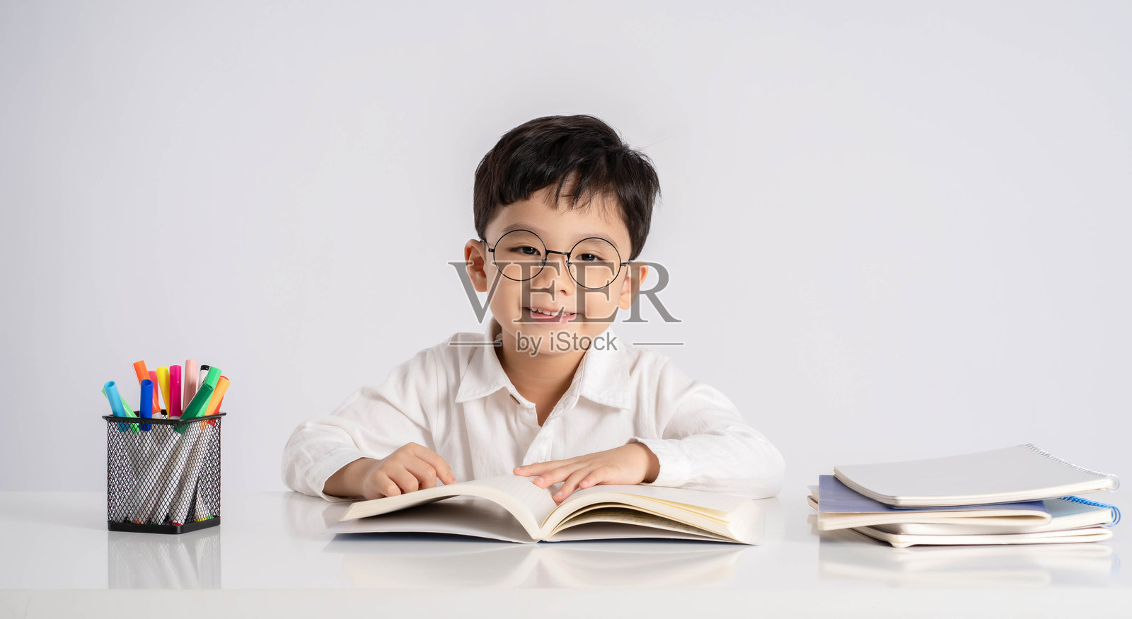 一个亚洲男孩在白色背景上学习的肖像照片摄影图片