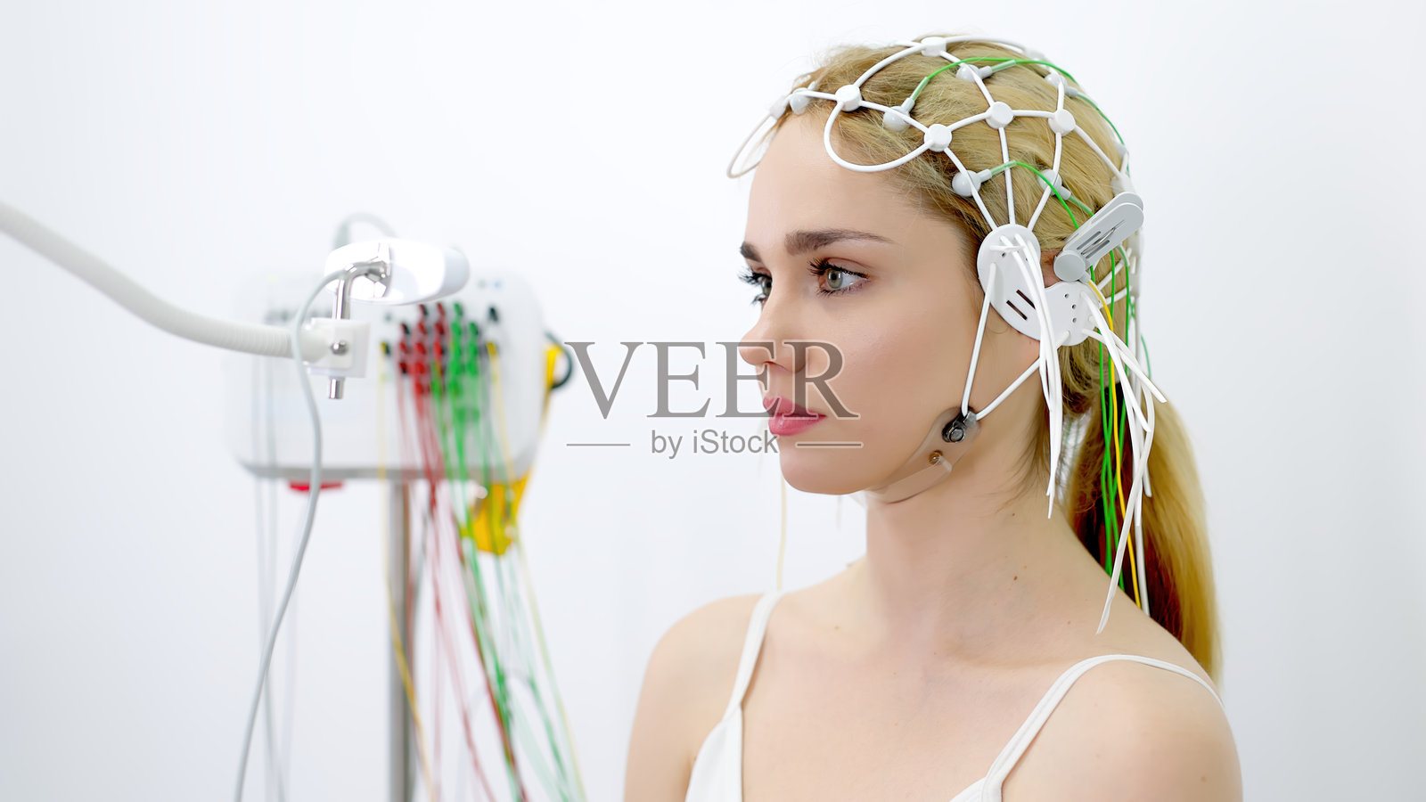 一名年轻女子在现代诊所接受脑电图测试,展示了先进的医疗技术和病人护理。理想的突出现代诊断程序和医疗保健创新。照片摄影图片