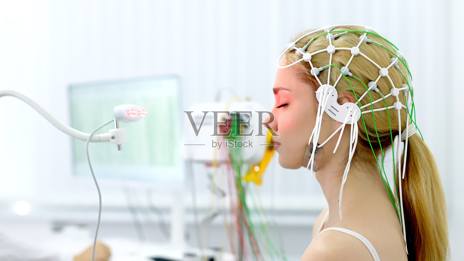 一名年轻女子在现代诊所接受脑电图测试,展示了先进的医疗技术和病人护理。理想的突出现代诊断程序和医疗保健创新。照片摄影图片
