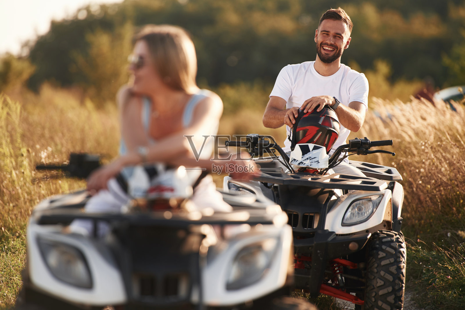 在球场上享受旅程。一男一女坐在户外的全地形车上照片摄影图片