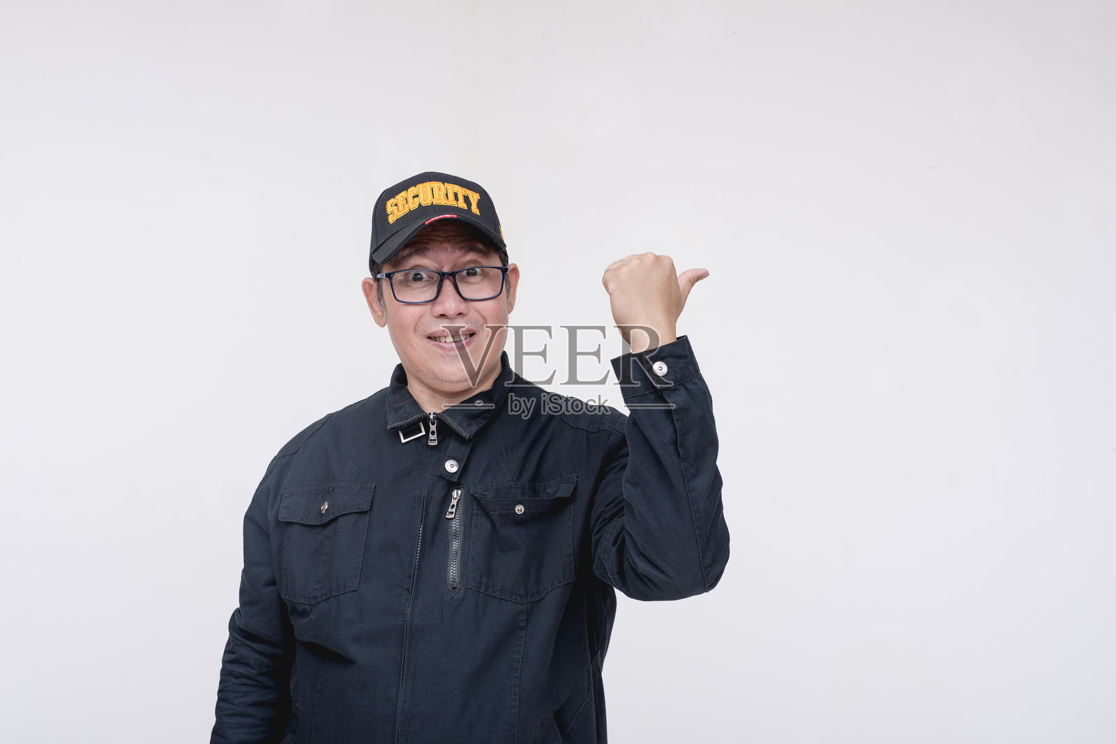 一名亚洲男性保安急切地用拇指指着右边。指导或建议某人的孤立在白色背景上。照片摄影图片