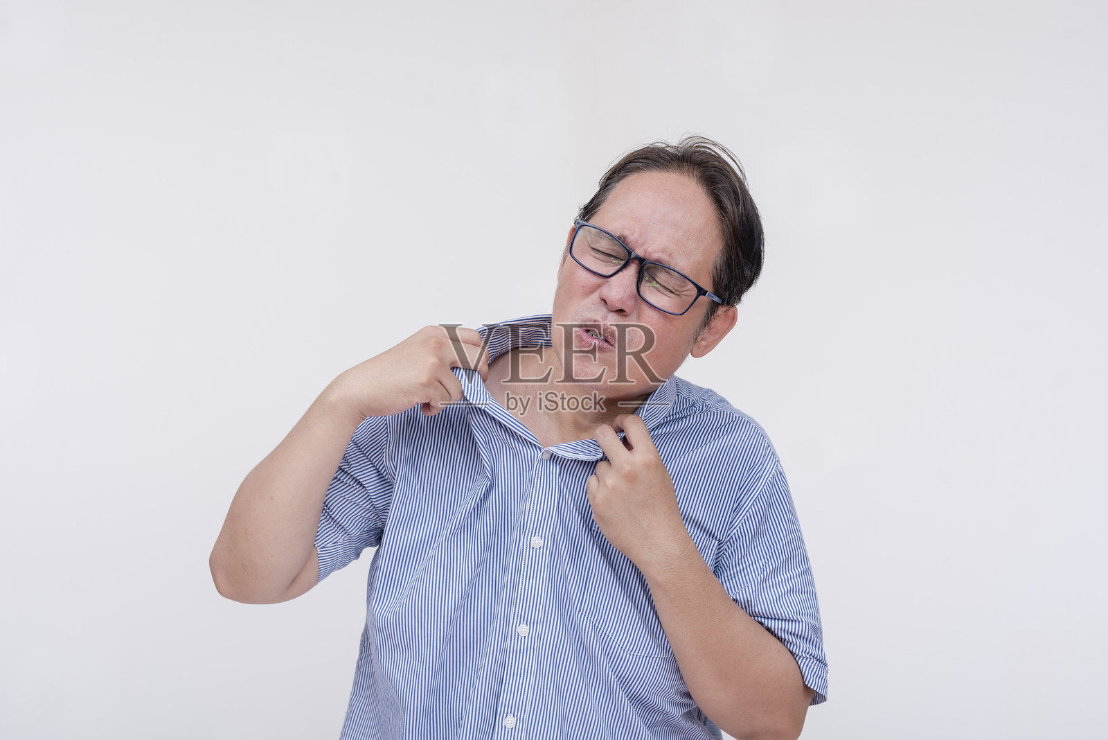 一名中年亚洲男子用扇子扇衬衣以抵御不舒服的高温。孤立在白色背景下。照片摄影图片