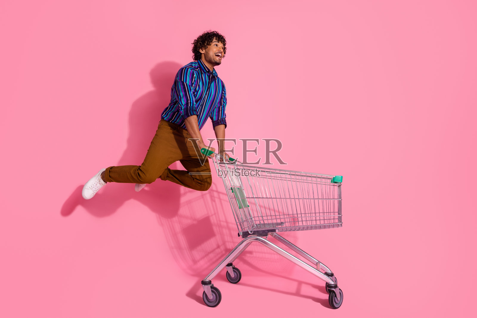 漂亮的年轻人跳市场手推车的全尺寸照片,在粉红色的背景上孤立的空间照片摄影图片