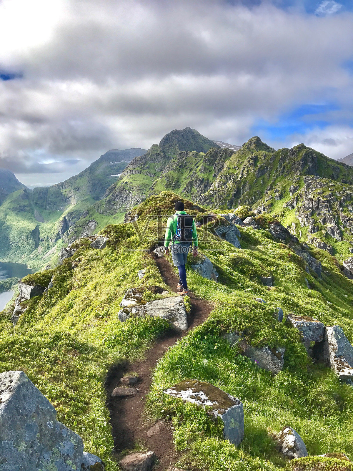 男性徒步旅行者在罗弗敦多云的天空下走在山路上照片摄影图片