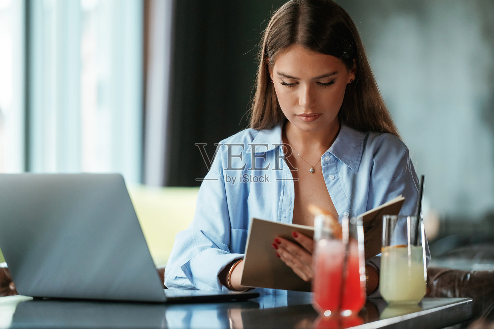 专注于工作。拿着笔记本电脑的美女在酒吧里照片摄影图片