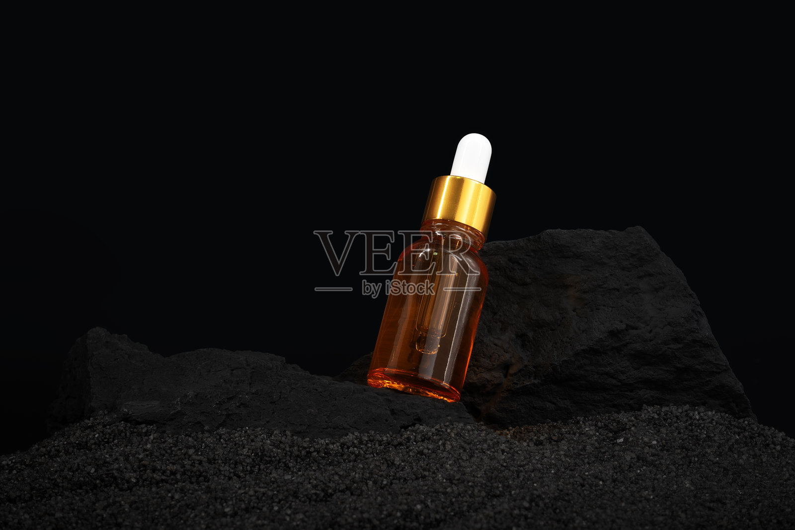 把瓶子和石头扔在黑沙滩上。血清瓶模拟照片摄影图片