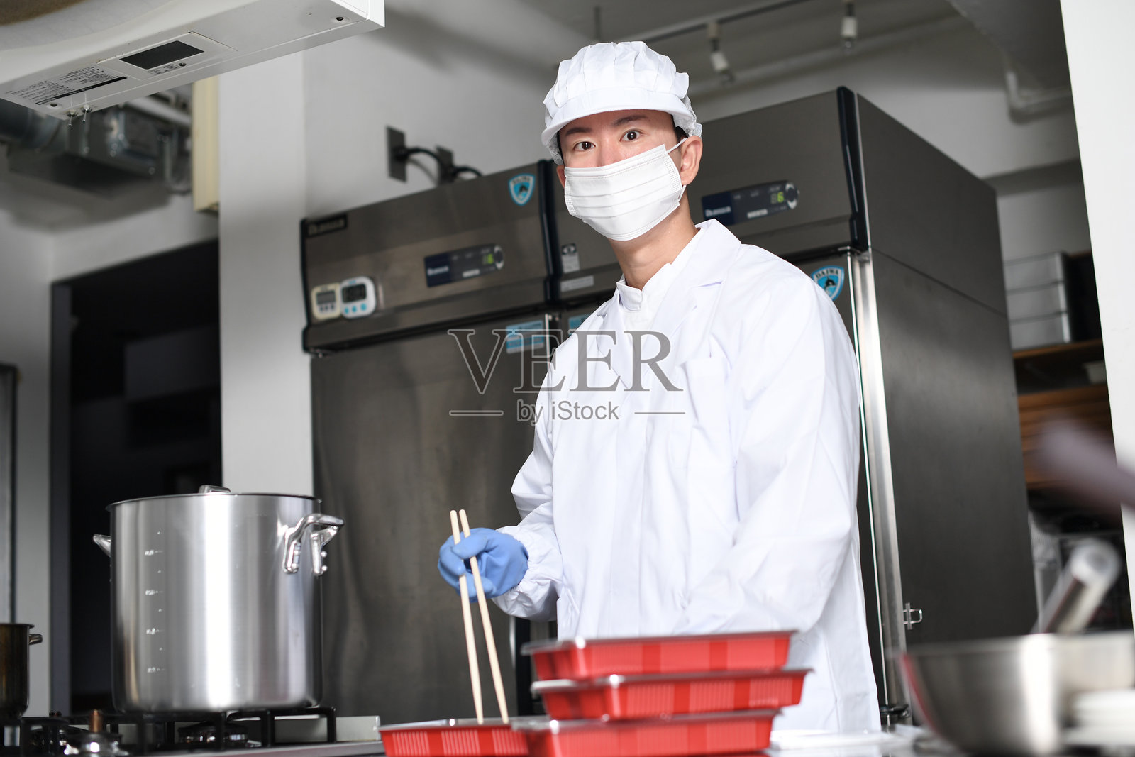 一名穿着干净西装的男厨师将食材装进便当盒照片摄影图片