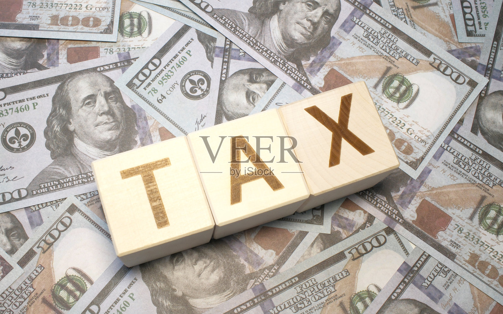 “税收”文字在木制立方体与金钱美元的背景照片摄影图片