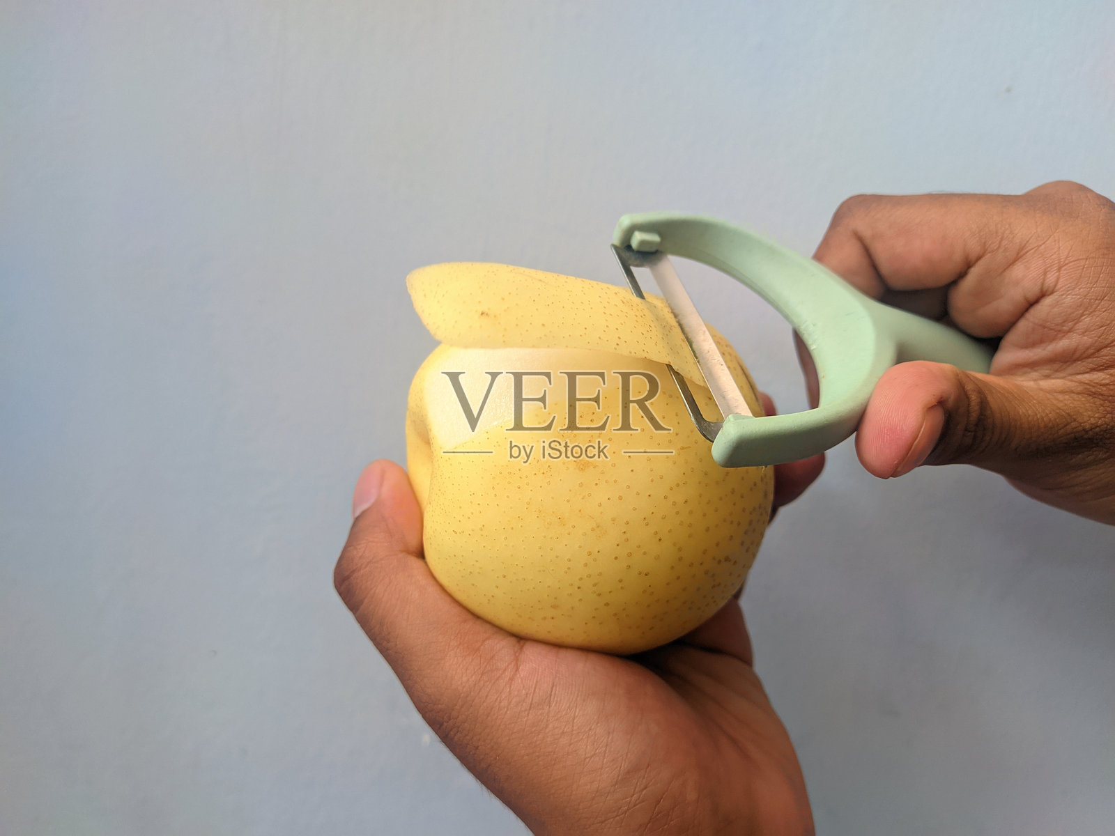 用绿色蔬菜削皮器削梨皮照片摄影图片