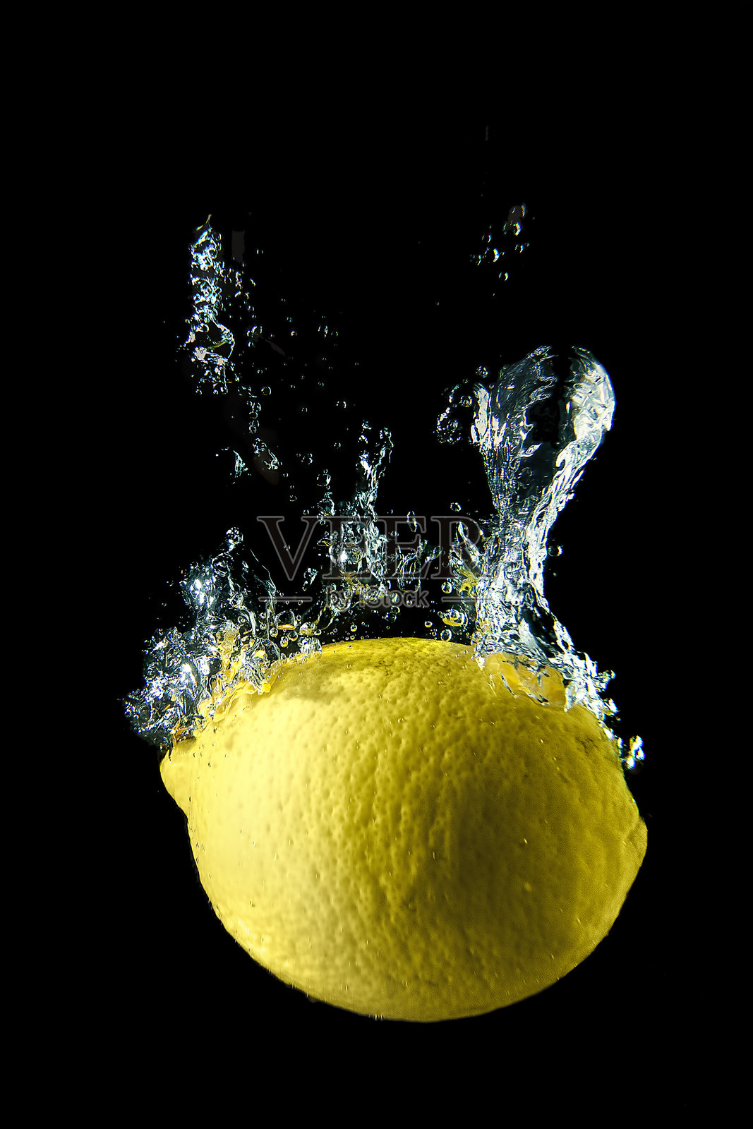 柠檬落入水中的特写,黑色背景照片摄影图片