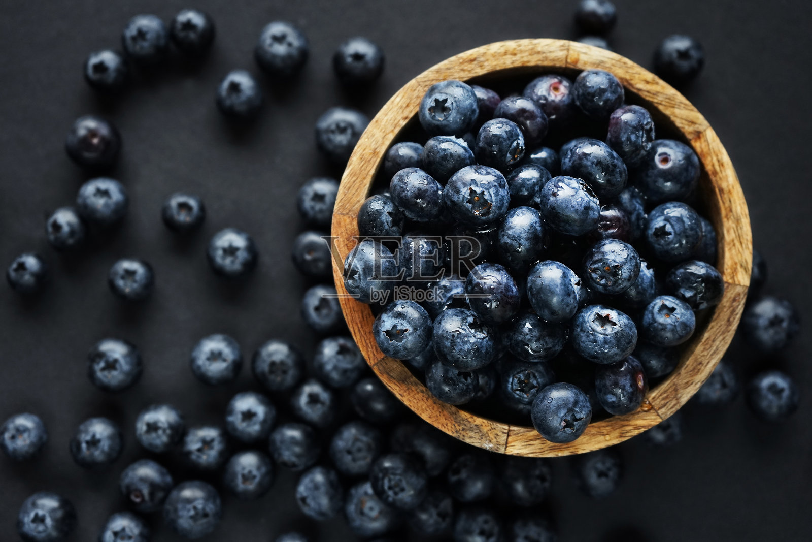 木碗里的新鲜蓝莓,旁边是散落的蓝莓照片摄影图片