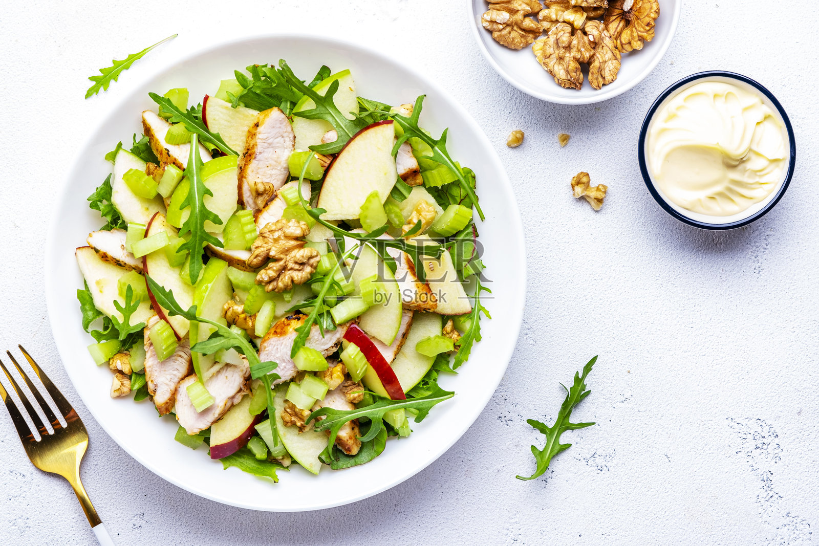 老式沙拉,搭配鸡肉、红苹果、青苹果、生芹菜、生菜和核桃,白色背景,俯视图照片摄影图片