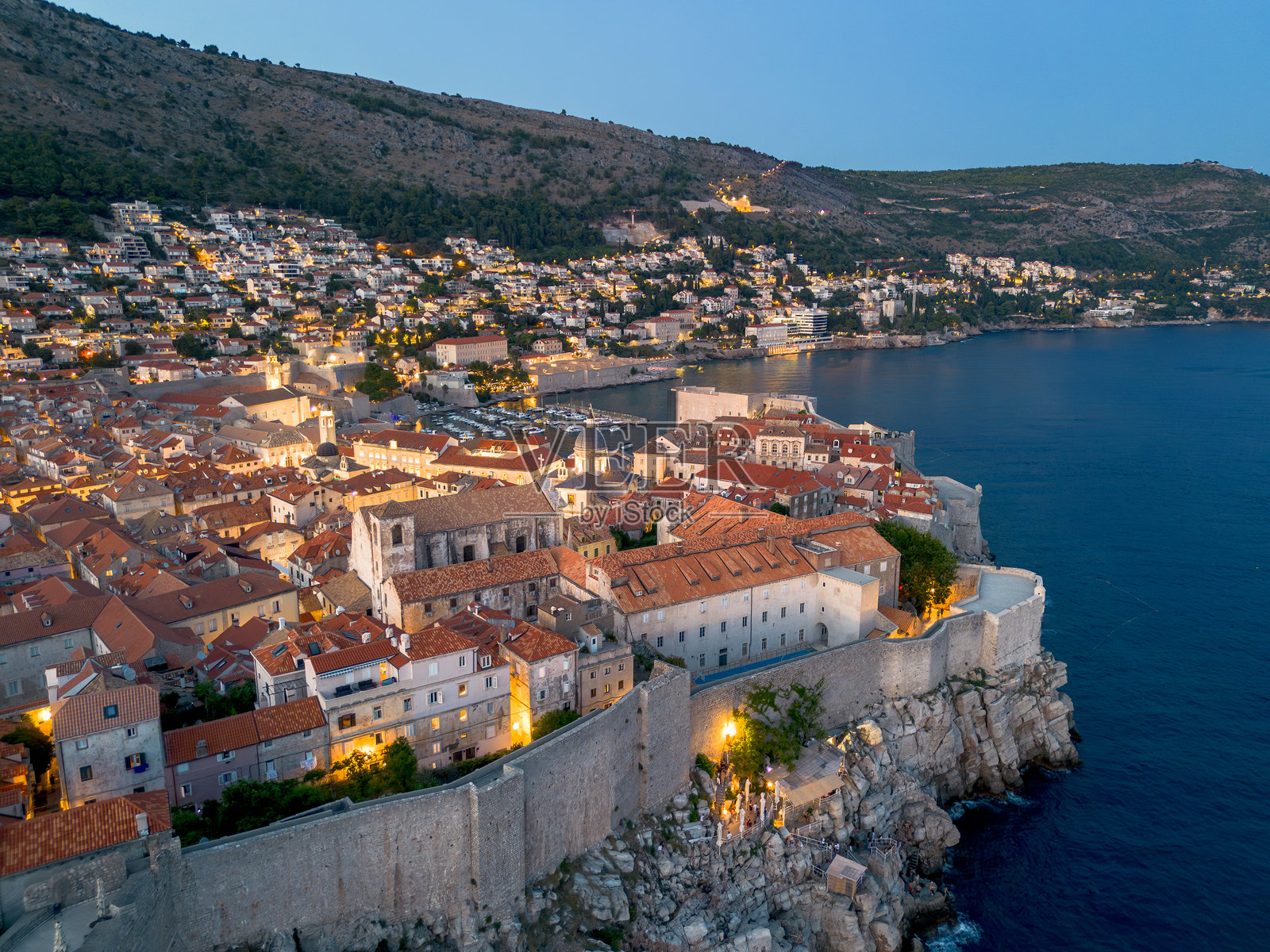 在亚得里亚海的克罗地亚,杜布罗夫尼克是一座历史悠久的古城。蓝色小时彩色城市景观与防御墙,狭窄的照明街道,瓦片屋顶和中心照片摄影图片
