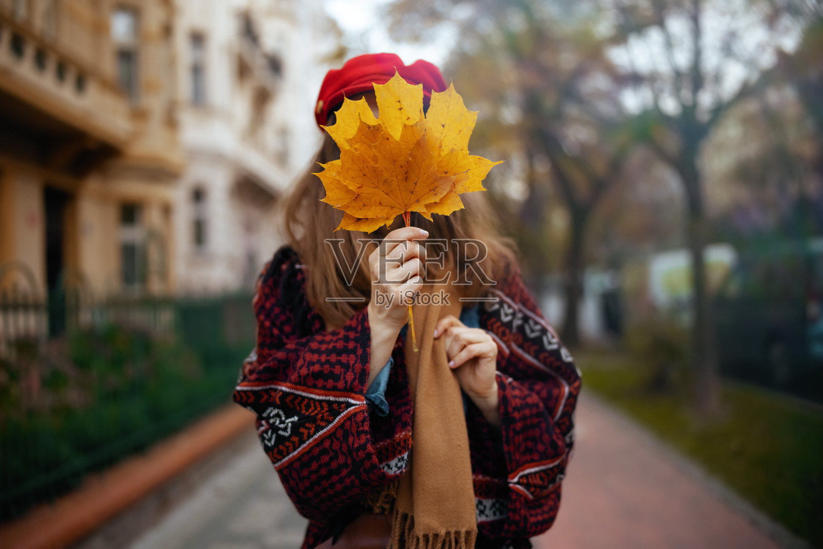 时髦的女性戴着红帽子,戴着秋叶和围巾照片摄影图片