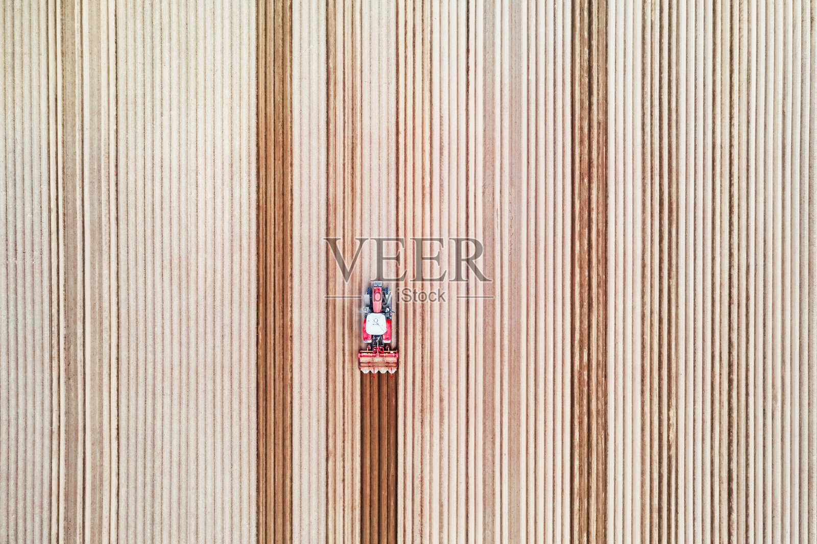 孤零零的拖拉机开在农田上,犁地成行照片摄影图片