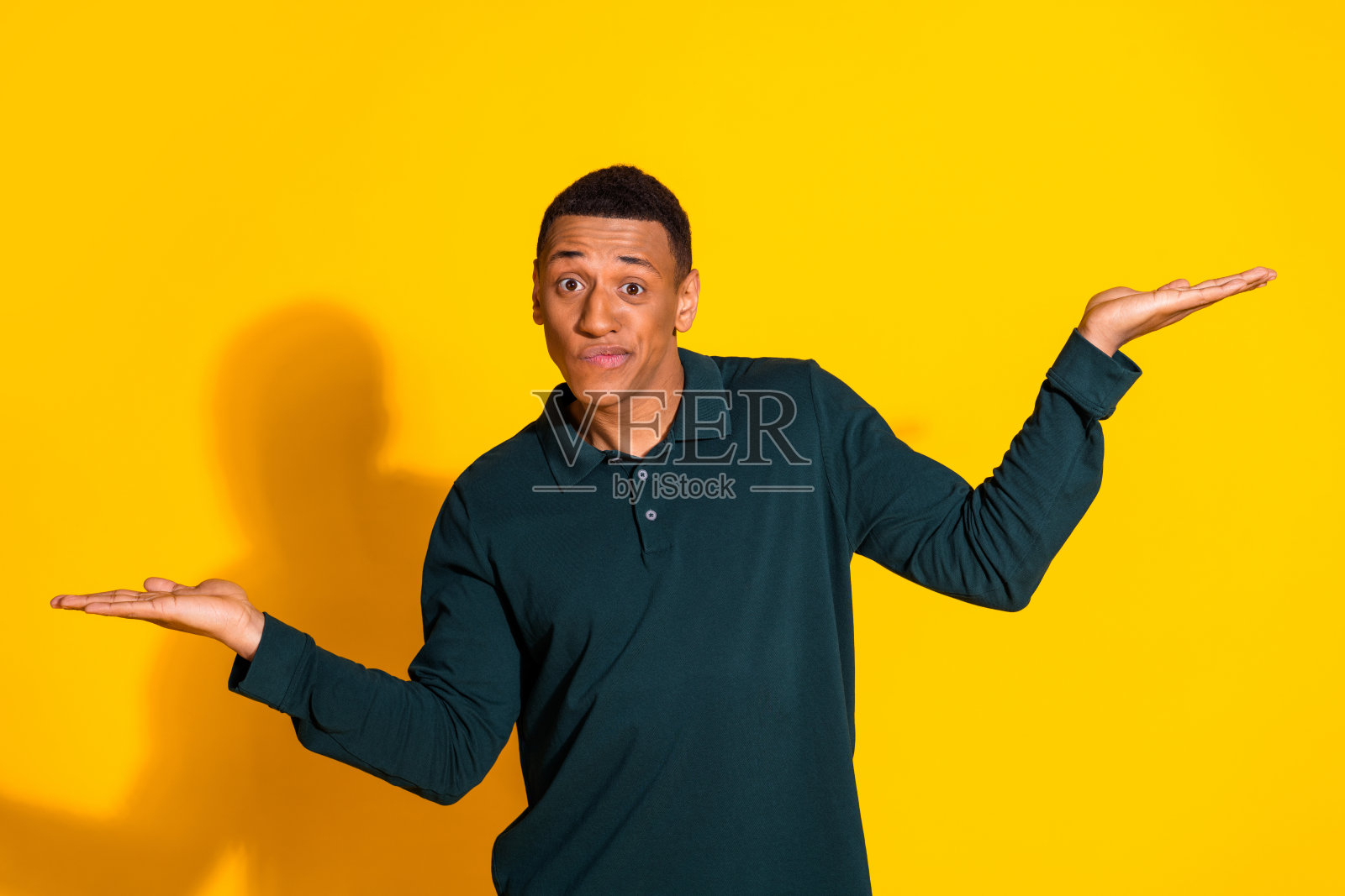 漂亮的年轻人手持空的空间尺度穿着套头衫孤立在明亮的黄色背景照片摄影图片