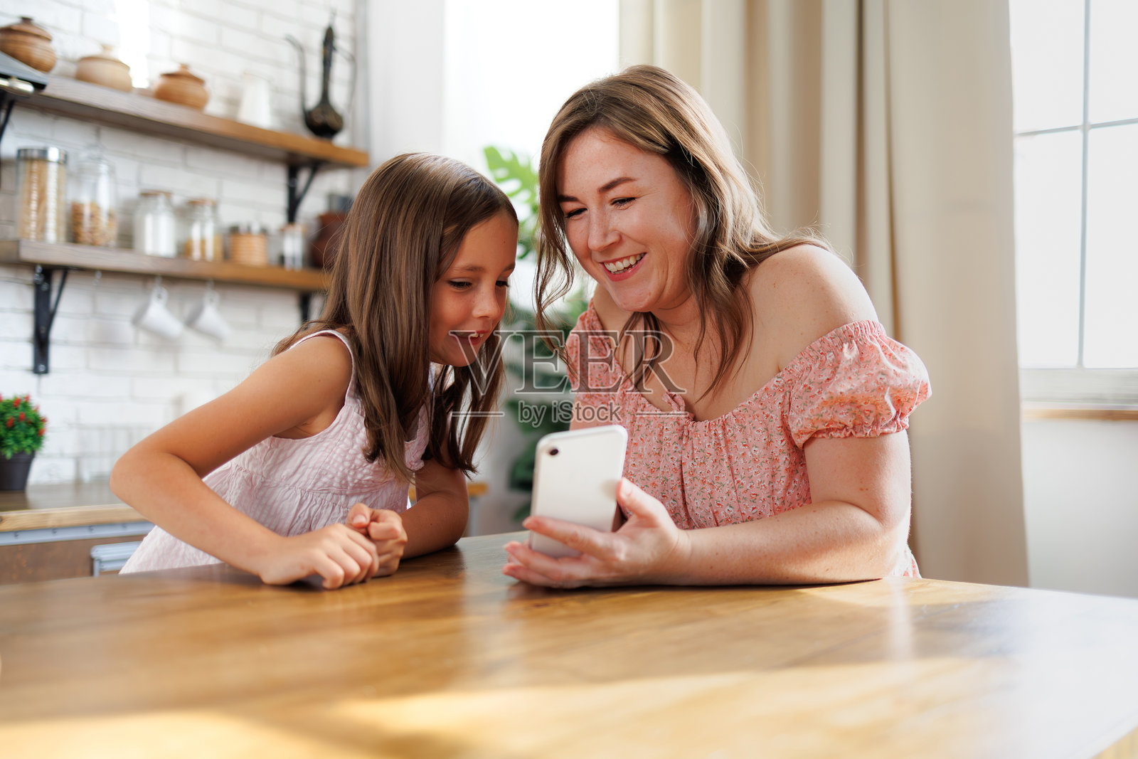 欢快的母女俩在厨房一起使用智能手机照片摄影图片