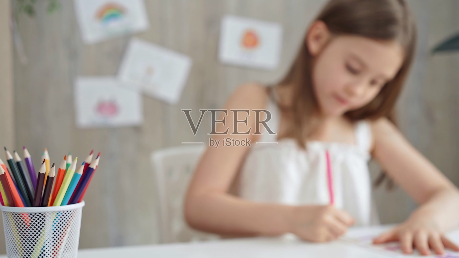 桌子上彩色铅笔的特写,背景是一个富有创造力的年轻女孩在画画照片摄影图片