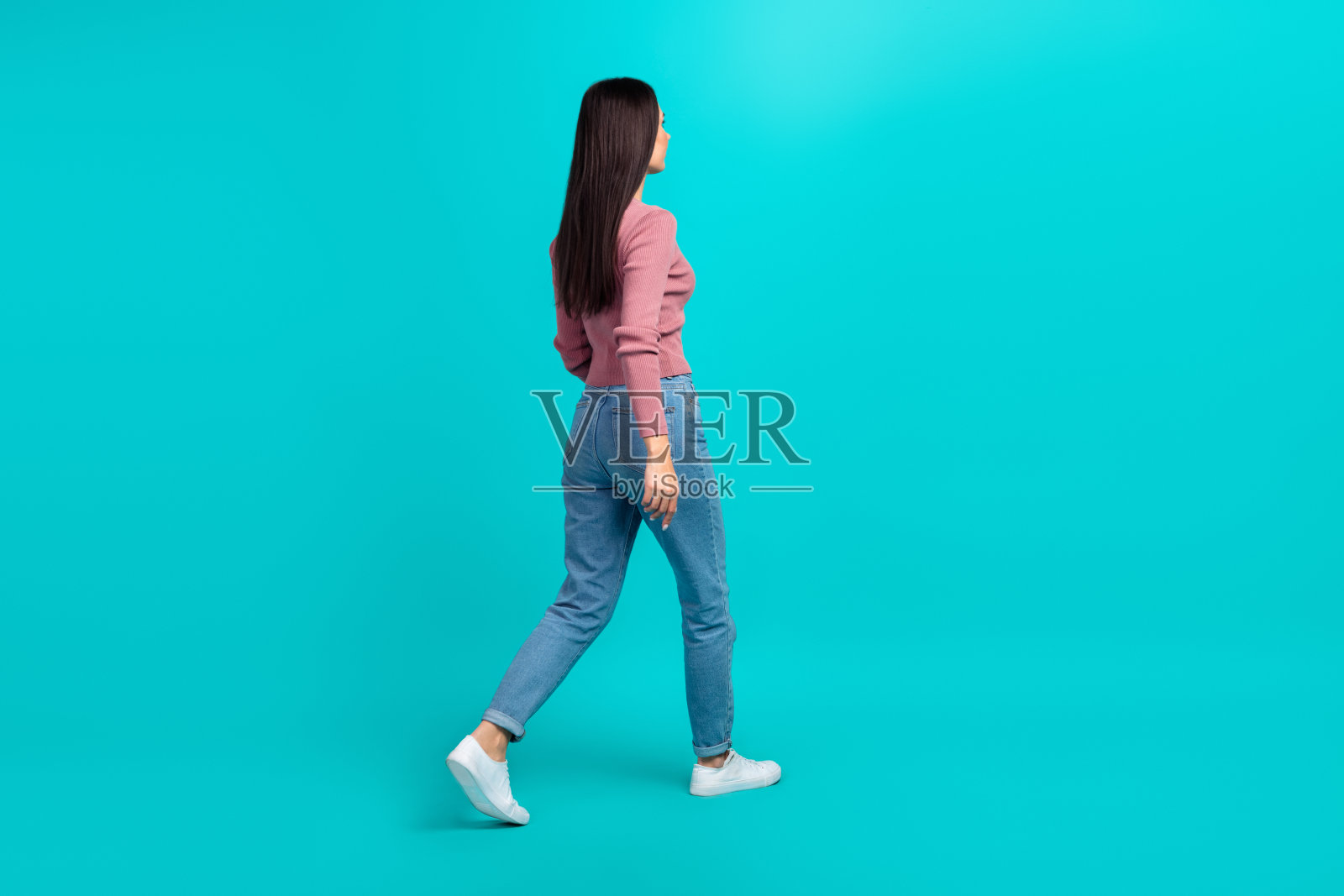 在绿松石色的背景上,行走的年轻人的全长侧面肖像看起来很空旷照片摄影图片