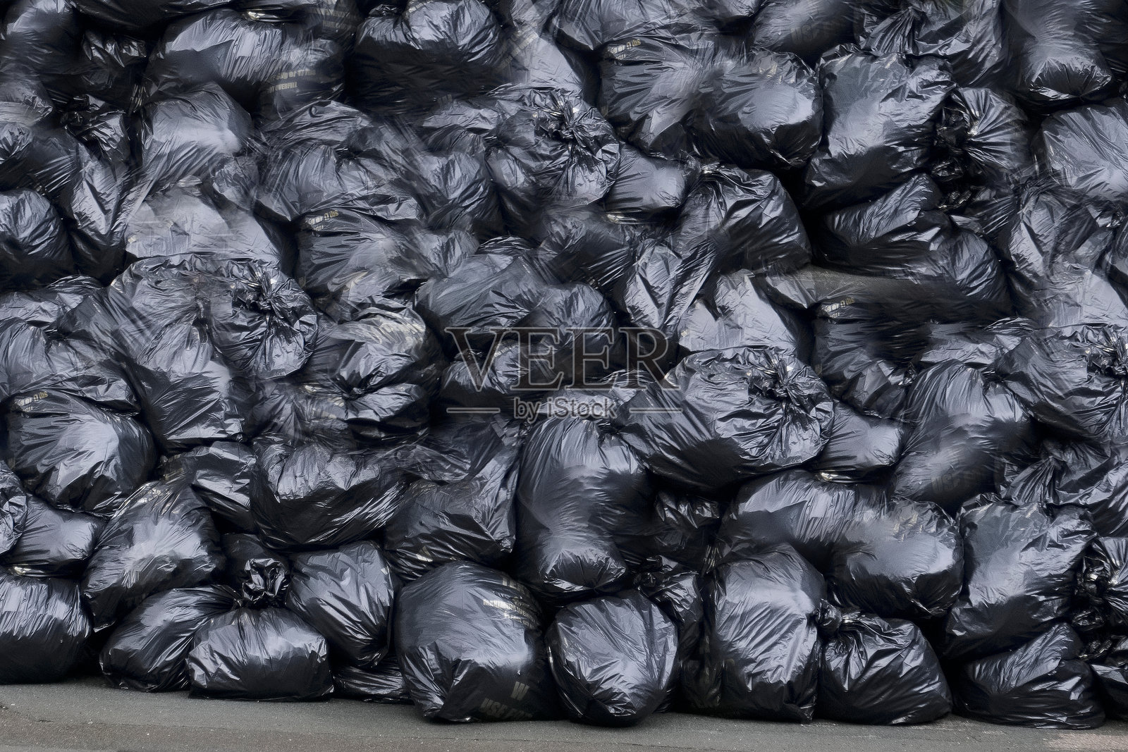 在垃圾收集罢工期间,黑色塑料垃圾袋装满并被遗弃在街上照片摄影图片