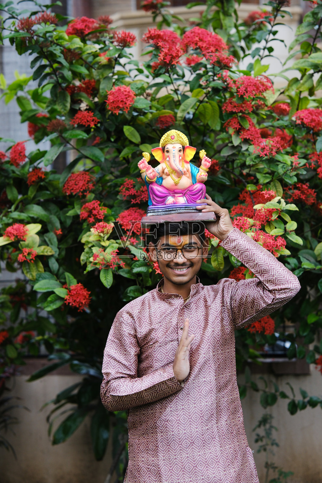 一个额头上戴着毗湿奴教头巾的印度年轻人,正在欢迎他尊敬的神——甘帕蒂。照片摄影图片