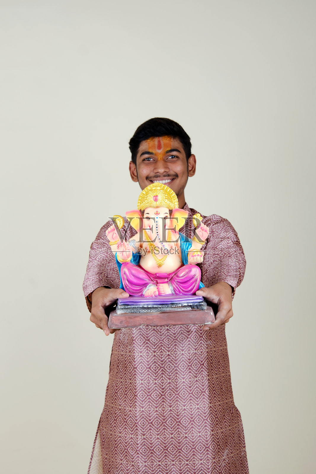 一个额头上戴着毗湿奴教头巾的印度年轻人,正在欢迎他尊敬的神——甘帕蒂。照片摄影图片